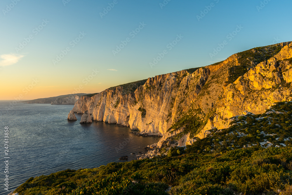 Greece, Zakynthos, Cliffs alongside silent ocean in warm sunset light enchanting mood Greece, Zakynthos, Cliffs alongside silent ocean in warm sunset light enchanting mood