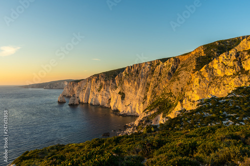 Greece, Zakynthos, Cliffs alongside silent ocean in warm sunset light enchanting mood