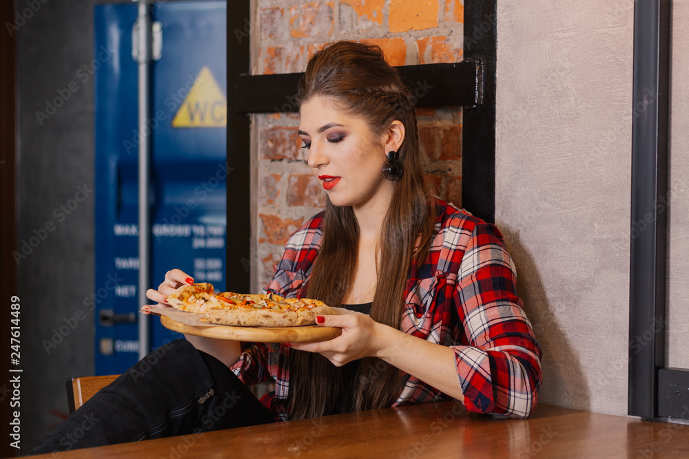 Beautiful and sexy girl sitting by the window in a cafe and eating pizza. Beautiful and sexy girl sitting by the window in a cafe and eating pizza.