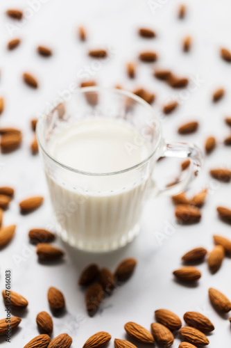 Almond milk in a glass surrounded by organic almonds