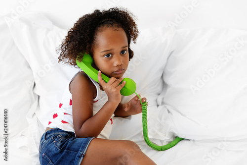 Girl listens to green corded toy phone photo