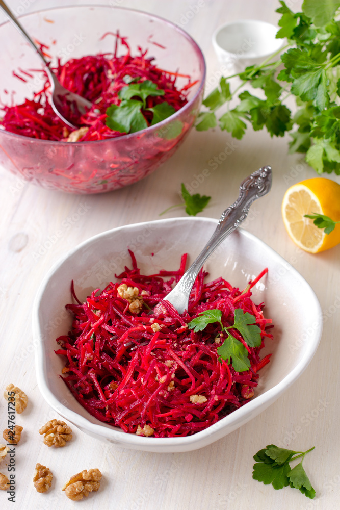 Healthy raw vegan beetroot salad with carrot and walnuts in a bowl on white wooden table. Natural organic food concept. Healthy diet Healthy raw vegan beetroot salad with carrot and walnuts in a bowl on white wooden table. Natural organic food concept. Healthy diet