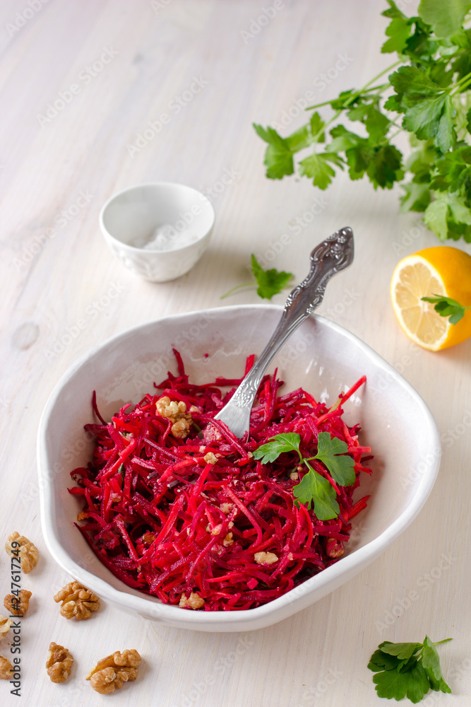 Healthy raw vegan beetroot salad with carrot and walnuts in a bowl on white wooden table. Natural organic food concept. Healthy diet Healthy raw vegan beetroot salad with carrot and walnuts in a bowl on white wooden table. Natural organic food concept. Healthy diet