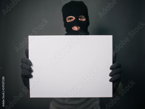 Bild auf Leinwand A man in a black mask holds a white sheet