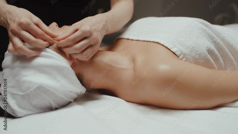 Woman receiving facial massage in spa lying on massage table. Wellness body and skin care, face treatment, receiving rejuvenation procedure Woman receiving facial massage in spa lying on massage table. Wellness body and skin care, face treatment, receiving rejuvenation procedure