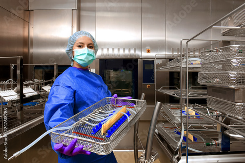 A young woman works in a hospital as a  medical hygiene technician. She is dressed  in special medical hygiene clothing and  carries out hygiene disinfecting and logistic tasks.