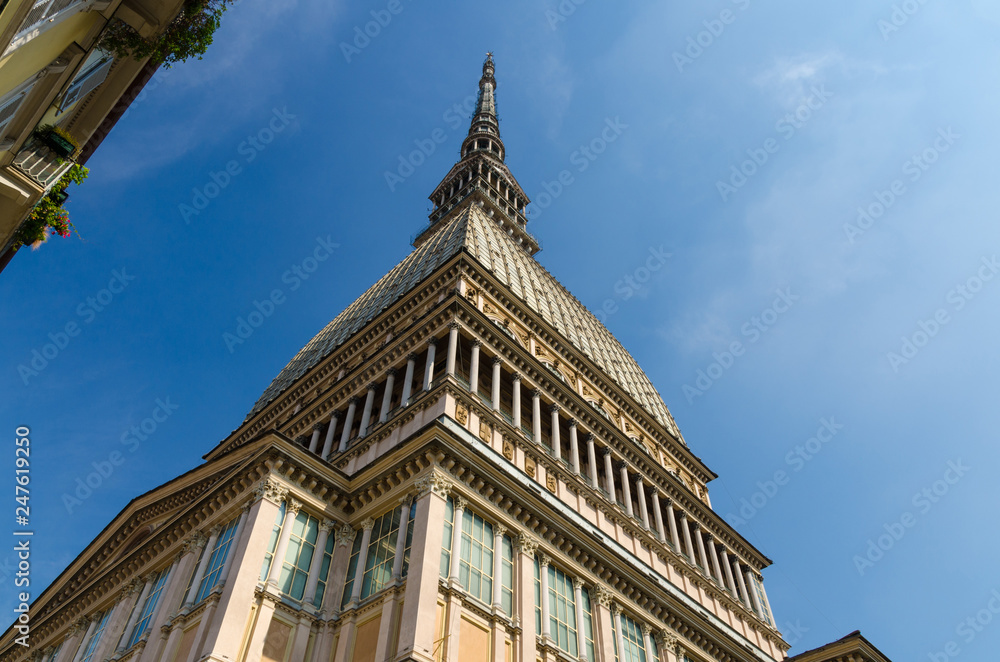 Mole Antonelliana tower building with spire steeple is major landmark and symbol of Turin Torino city, view from below, blue sky background, Piedmont, Italy
