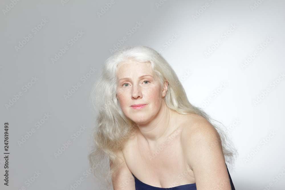 Headshot of an attractive mature woman with beautiful long gray hair in front of white background, copy space. Headshot of an attractive mature woman with beautiful long gray hair in front of white background, copy space.