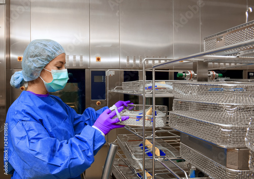 A young woman works in a hospital as a  medical hygiene assistant. She is dressed  in special medical hygiene clothing and  carries out hygiene disinfecting and logistic tasks.