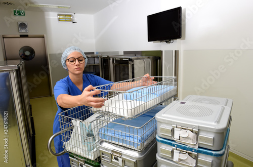 A young woman works in a hospital as a  medical hygiene assistant. She is dressed  in special medical hygiene clothing and  carries out hygiene disinfecting and logistic tasks.