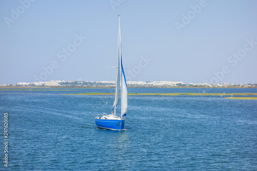 Sailing boat in the Formosa estuary with Olhao in the background. Algarve, Portugal