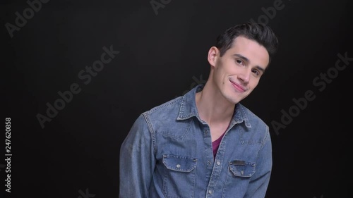 Closeup portrait of young cute caucasian man being shy and ablush smiling and looking at camera with the background isolated on black photo