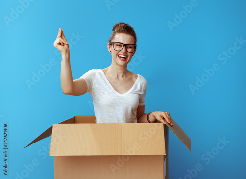 happy woman with fingers snapping in cardboard box on blue