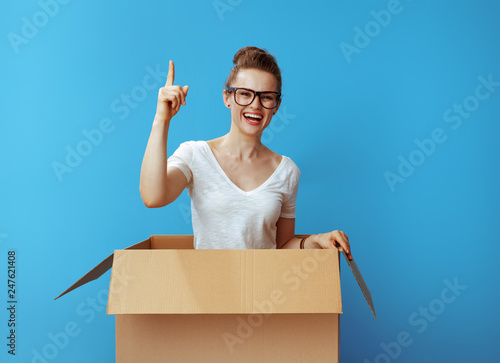 happy young woman in cardboard box got idea on blue