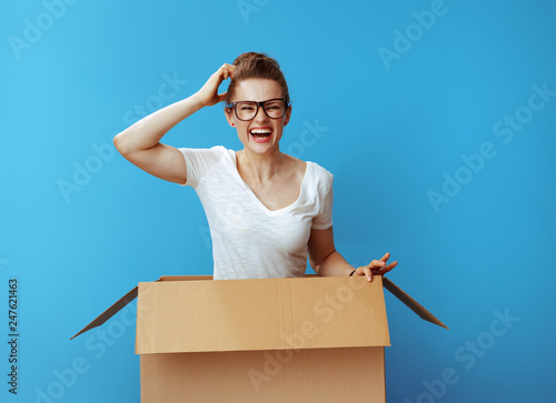 happy modern woman in white t-shirt in cardboard box on blue