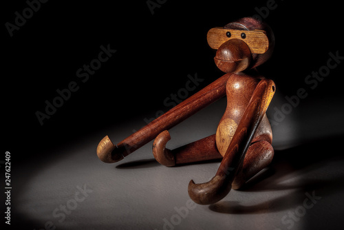 A wooden toy figure of a monkey in the dual spotlight
