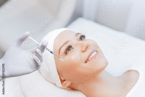 Woman receiving injections in cheekbones. Close up of hands of cosmetologist making injection in female cheekbones. Plastic surgery Cosmetology skincare concept. Injections of skin rejuvenat.