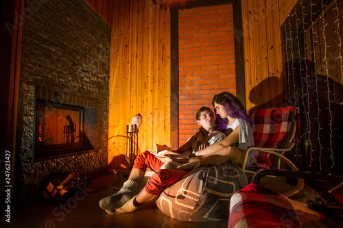 The couple is heated by the fireplace, embracing. Evening relaxation at home. Rest around the fireplace. Cozy home. Romantic atmosphere.