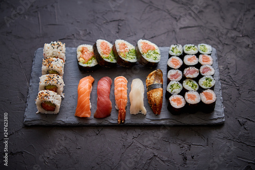 Sushi rolls set with salmon and tuna fish served on black stone board