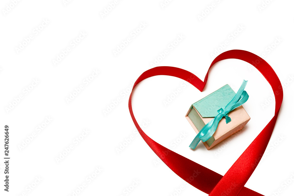 Pink-blue box for jewelry in the center of a silk ribbon made in the shape of a heart on a white background. Copy space Pink-blue box for jewelry in the center of a silk ribbon made in the shape of a heart on a white background. Copy space