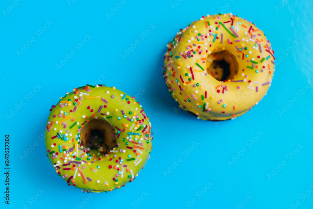 Two color donuts. Yellow and Green Donut on a blue background. Dessert Two color donuts. Yellow and Green Donut on a blue background. Dessert