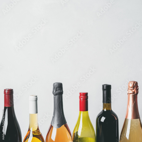 Tops from different kinds new bottles of champagne, white, red wine on light background