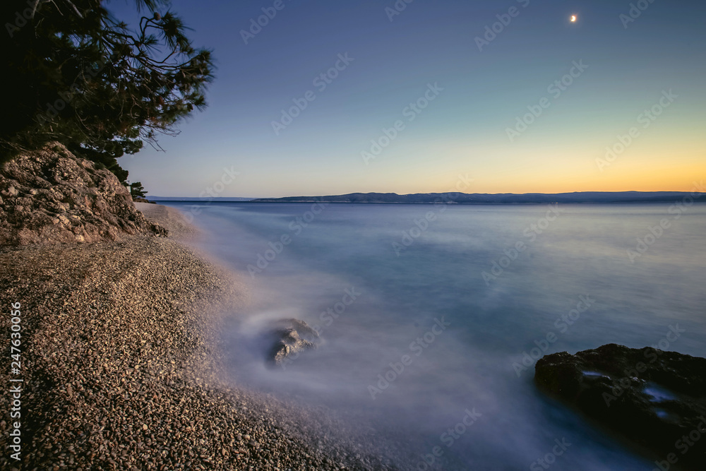 Vacation in Croatia. Pebble beach and the waves. Long exposure. Sunset in Dalmatia.