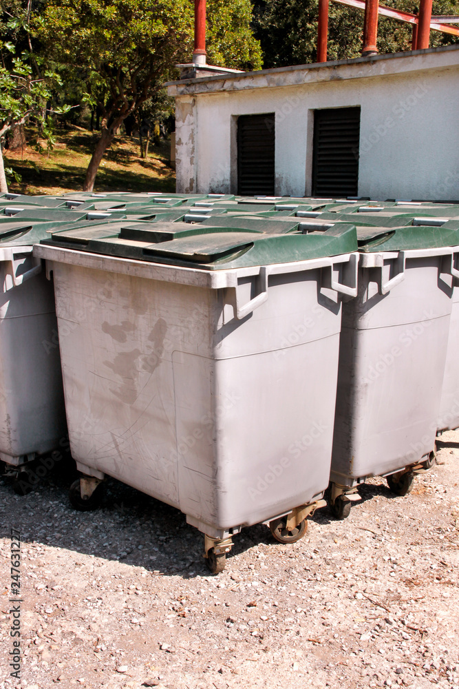 Large garbage containers, trash dumpsters and bins standing in row. Orderly stowed garbage cans ready for separate garbage collection. Environmentally friendly trash containers, recycle bins, tanks. Large garbage containers, trash dumpsters and bins standing in row. Orderly stowed garbage cans ready for separate garbage collection. Environmentally friendly trash containers, recycle bins, tanks.