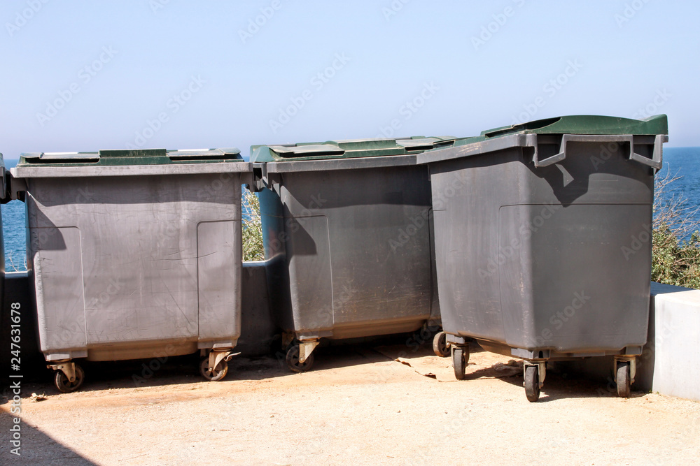 Large garbage containers, trash dumpsters and bins standing in row. Orderly stowed garbage cans ready for separate garbage collection. Environmentally friendly trash containers, recycle bins, tanks. Large garbage containers, trash dumpsters and bins standing in row. Orderly stowed garbage cans ready for separate garbage collection. Environmentally friendly trash containers, recycle bins, tanks.
