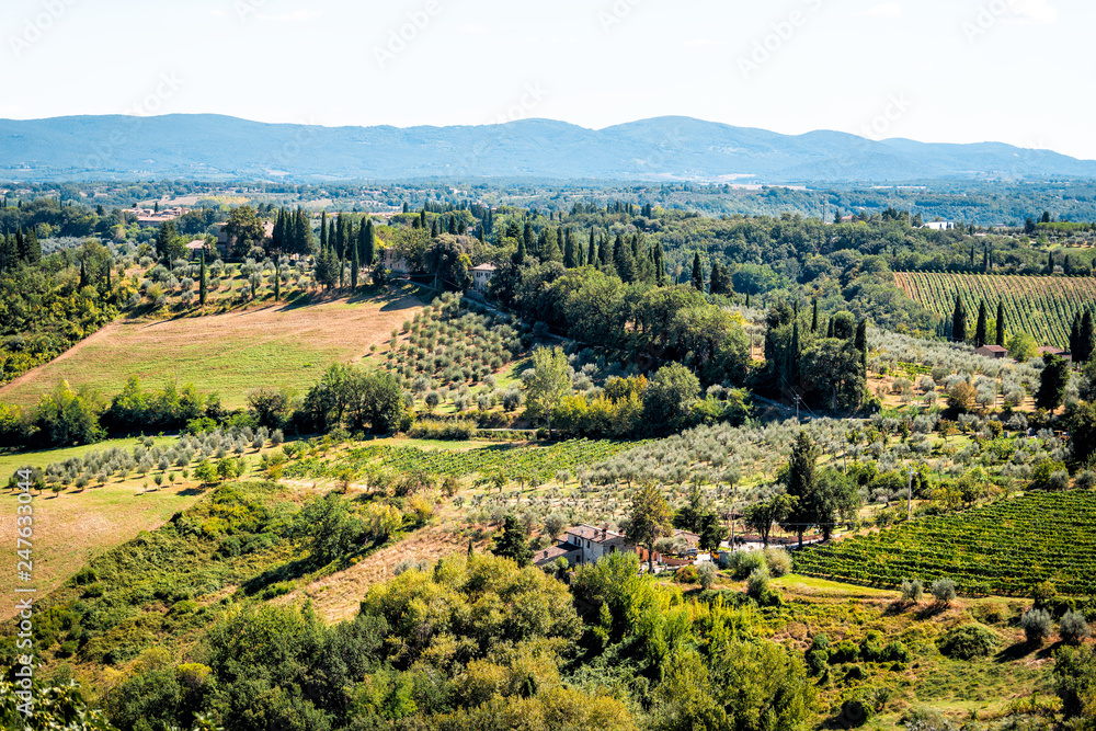 San Gimignano, Italy landscape of rolling hills with vineyards, wineries, villas in town village during sunny summer aerial high angle view with olive groves