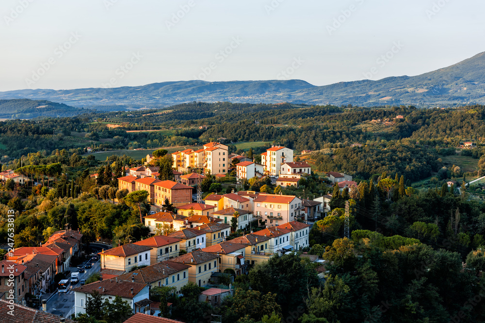 Chiusi village cityscape at sunrise in Umbria Italy with rooftop houses on mountain countryside and rolling hills