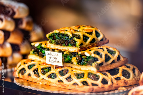 Colorful green baked lattice pastry tart dessert closeup in store window in Assisi in Umbria Italy on display in gourmet bakery Italian cafe with sign