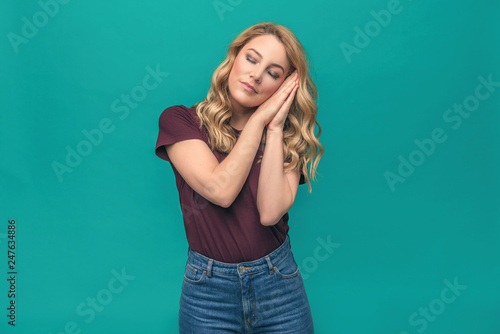 A woman standing asleep or dozing arms folded. Attractive blonde on a blue background. © Denis Rozhnovsky