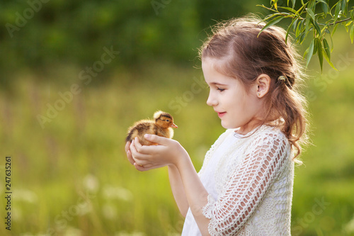 Canvas Print Little girl holding a cute duckling in the hands. Copy space