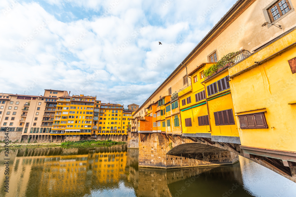 Florence, Italy Firenze orange yellow colorful buildings on Ponte Vecchio by Arno river during summer morning in Tuscany with nobody and reflection on water