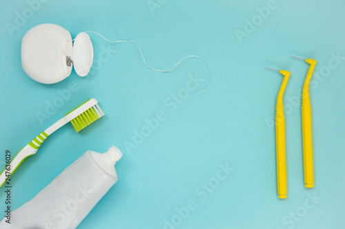 Teeth care, toothpaste, toothbrush and dental floss on blue background. Teeth cleaning brushing and flossing.