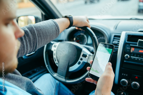 man hands on steering wheel using phone as navigator