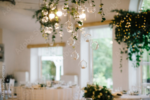 Little balls with candles hang from floral garland over wedding dinner table