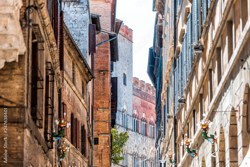 Siena, Italy Street in historic medieval old town village narrow alley in Tuscany with facade exterior architecture during sunny summer day