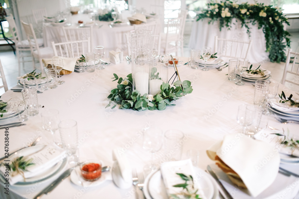 Wedding dinner table set. Classy white decor with greenery