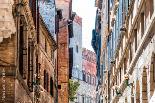 Siena, Italy Street in historic medieval old town village narrow alley in Tuscany with facade exterior architecture during sunny summer day