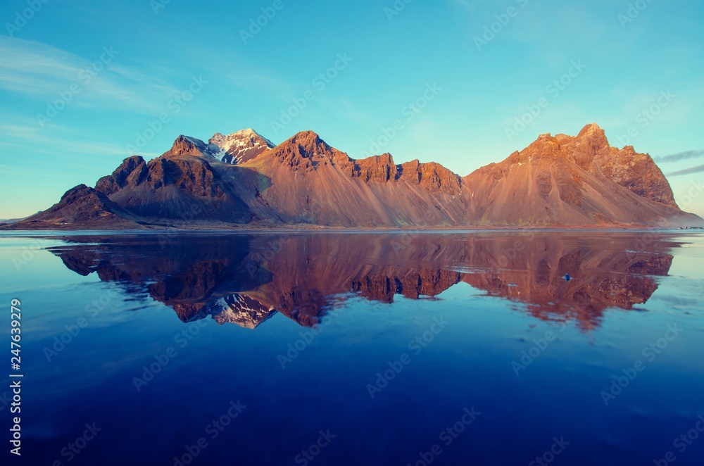 Jagged Mountain on Ice in Iceland with Carolina blue Sky and dark blue sky in reflection 