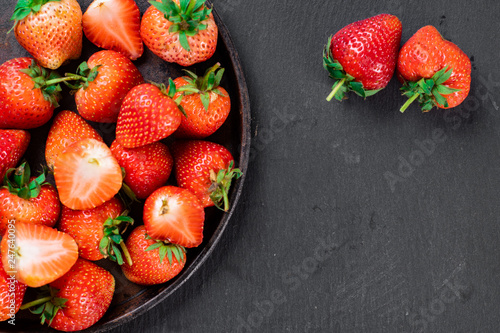 Fresh strawberry in wrought plate on  dark board.  photo