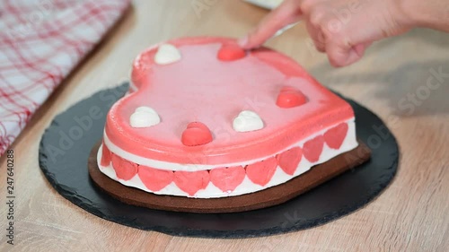 Confectioner decorating heart-shaped mousse cake. Cake for Valentines day. photo