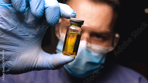Male doctor in work uniform wearing gloves with goggles goggles examines in vitro analysis. Concept of: Proffessional doctor, Urine tests, Laboratory assistant, All protective kit.