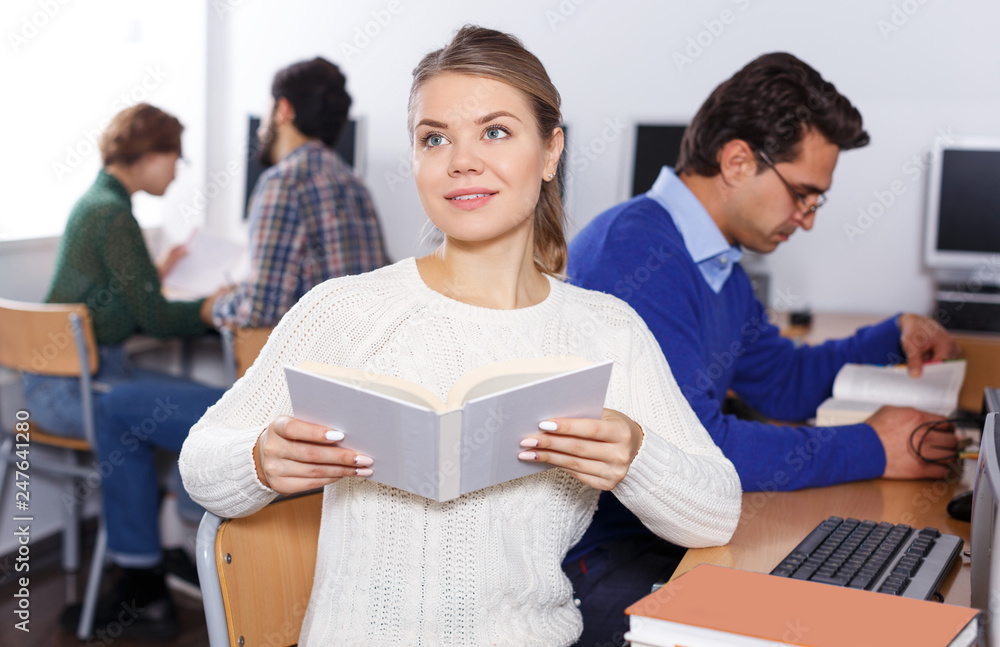 Fototapeta premium female student reading textbook while studying
