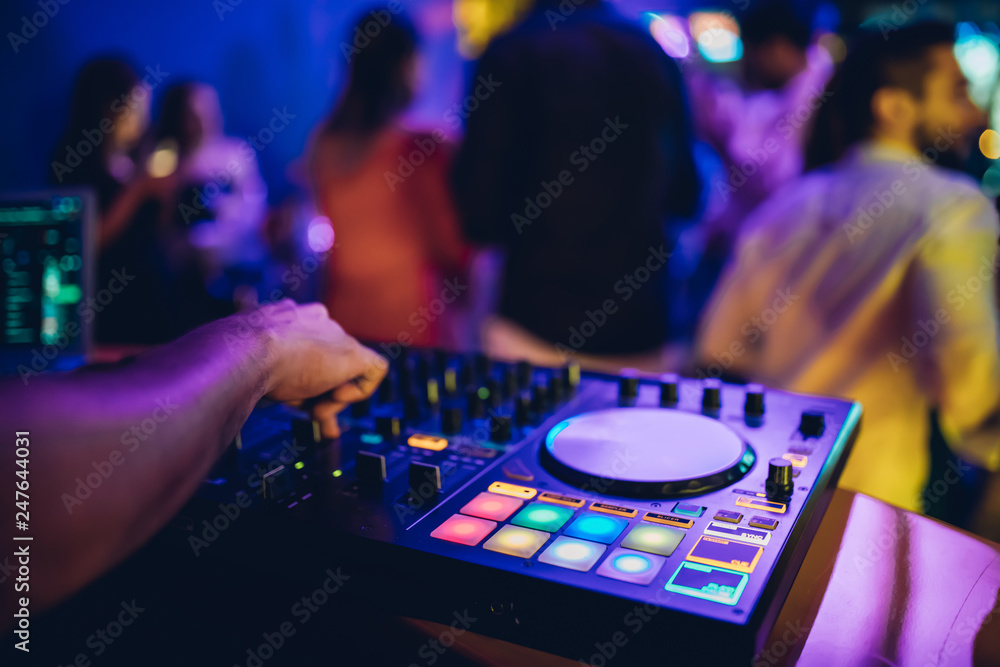 DJ plays live set and mixing music on turntable console at stage in the night club. Disc Jokey Hands on a sound mixer station at club party. DJ mixer controller panel for playing music and partying. DJ plays live set and mixing music on turntable console at stage in the night club. Disc Jokey Hands on a sound mixer station at club party. DJ mixer controller panel for playing music and partying.