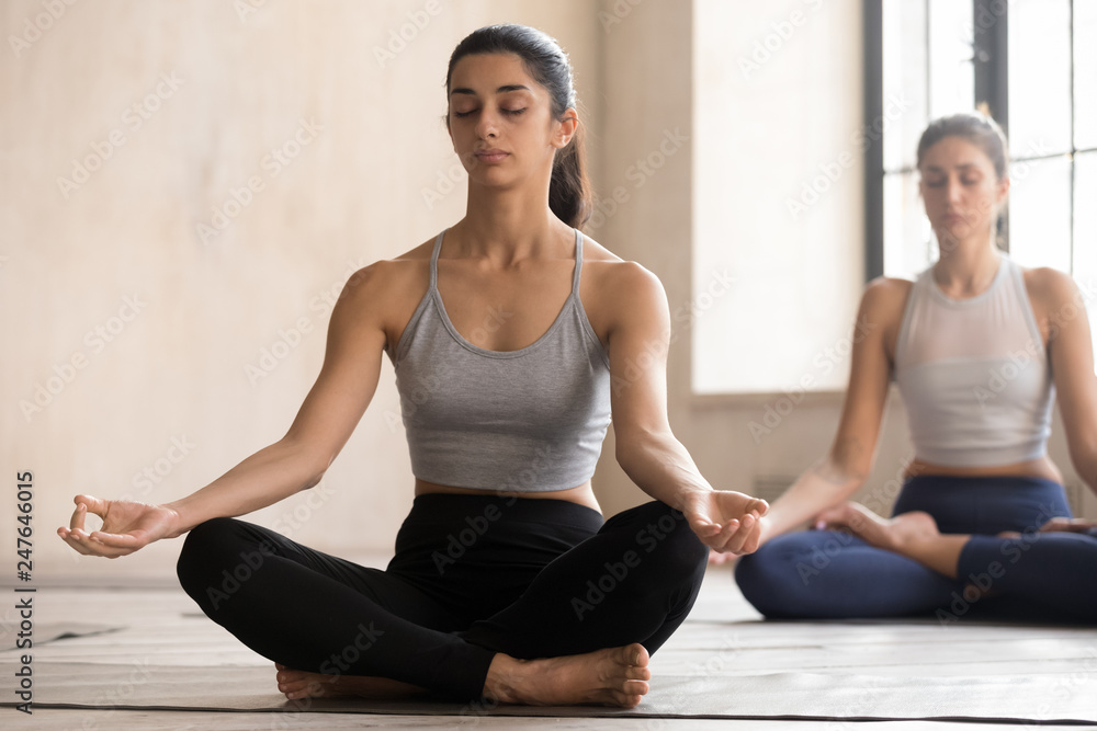 Toned girl sit on mat practicing yoga with eyes closed Toned girl sit on mat practicing yoga with eyes closed