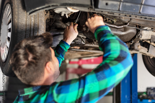 Portrait of mechanic repairing with a wrench a lifted car .