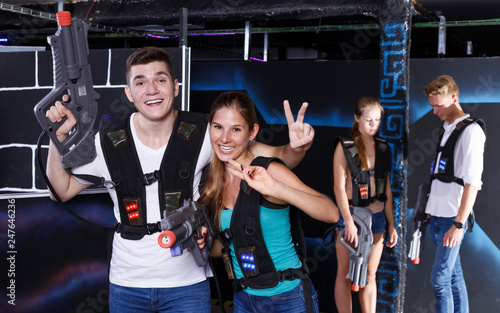 Team of laser tag winners guy and smiling girl and losers team in background